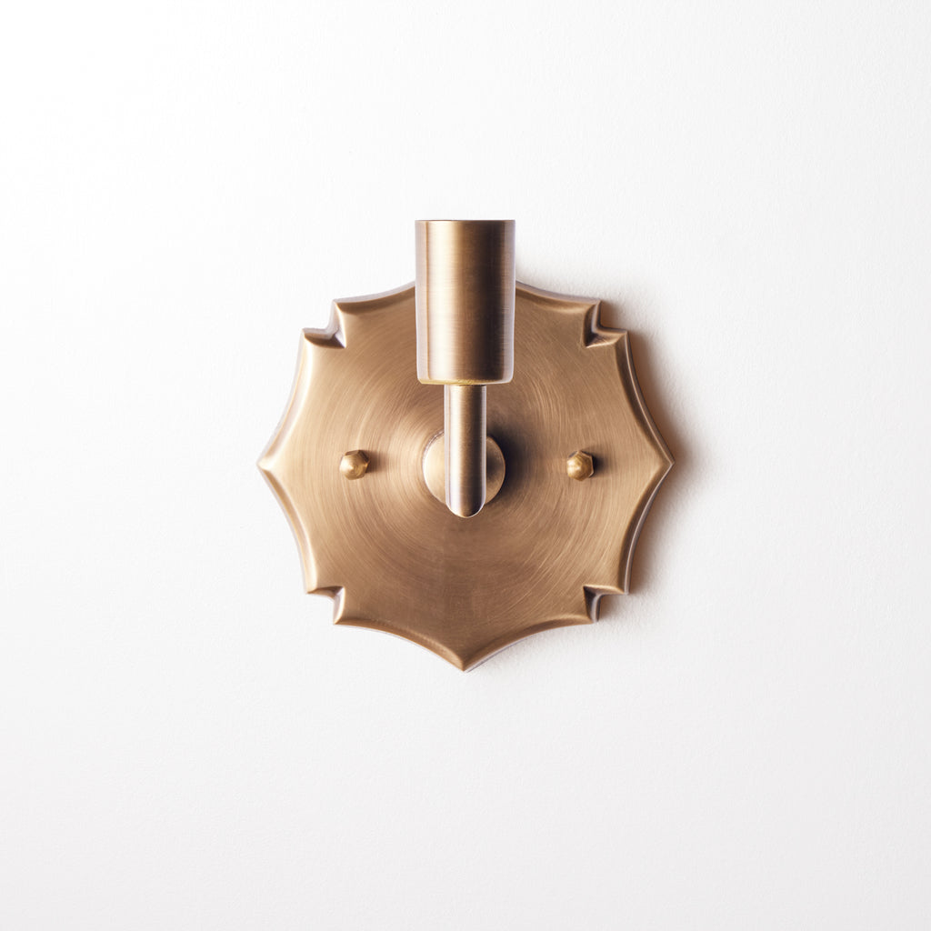 single insignia wall fixture in antiqued brass