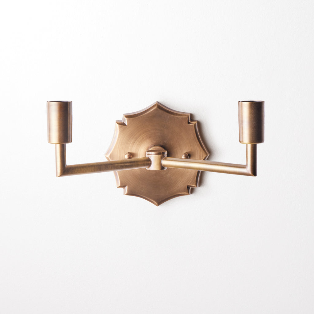 Double insignia wall fixture in antiqued brass